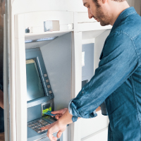 A man using debit card at ATM machine