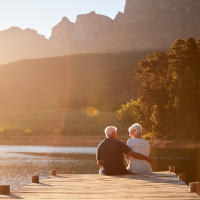 A mature couple sitting on dock during sunset